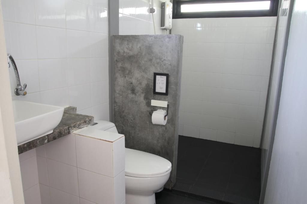 A small bathroom with a white toilet, a sink, and a shower stall.