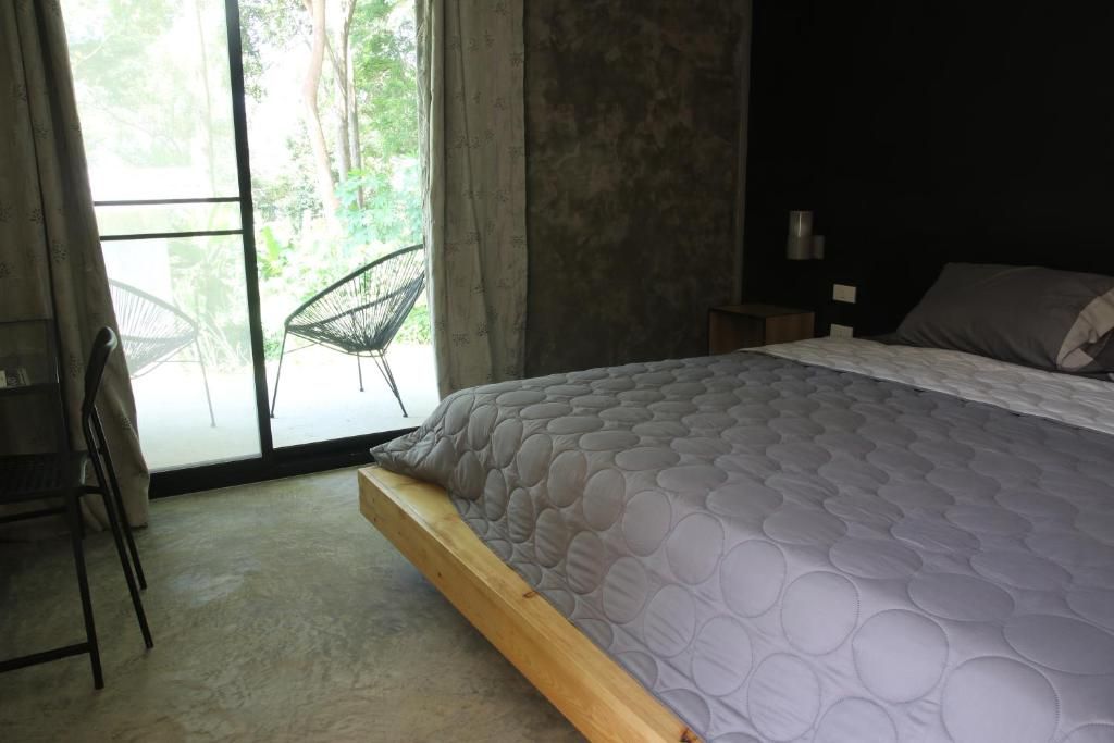 Une chambre à coucher avec un lit, une chaise et une vue à travers une porte vitrée.