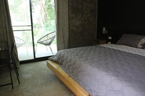 Un dormitorio con una cama, una silla y vistas a través de un ventanal.