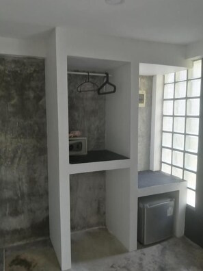 Una habitación con refrigerador integrado, perchero y ventana con diseño de cuadrícula.