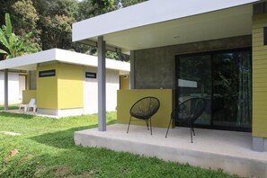Un bâtiment moderne doté d’un toit plat, d’un espace extérieur couvert avec des chaises et d’une entrée avec une porte en verre.