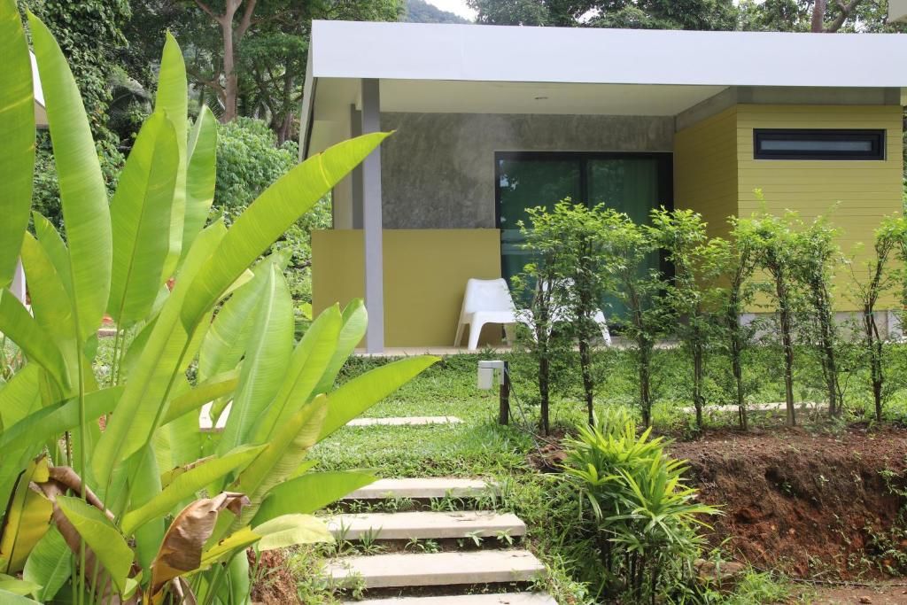 A modern building with a yellow facade, a white exterior, and a small garden area with steps leading to a white chair.