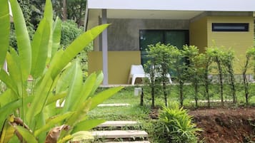 A modern building with a yellow facade, a white exterior, and a small garden area with steps leading to a white chair.