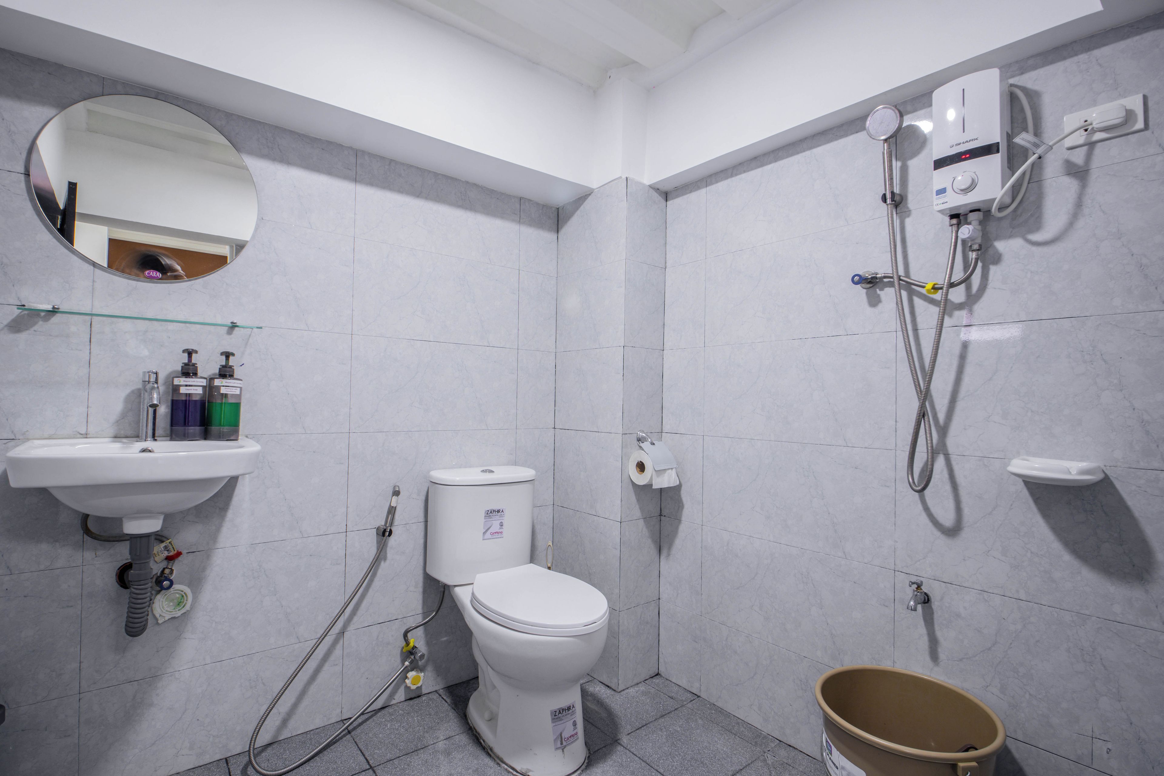 A bathroom with a sink, toilet, mirror, and shower.