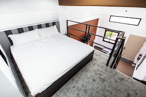 Un dormitorio con cama, mesita de noche, ventana y puerta.
