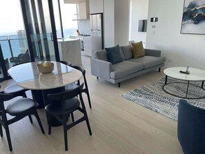 Un saló modern amb zona de menjador, un sofà, una taula de centre i vista al mar.