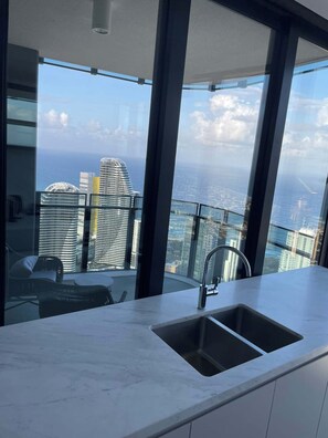 A modern kitchen with a large window overlooking a cityscape. - Panoramic Ocean Luxe Lv54  2Bed 2Bath Parking Inc (Broadbeach)