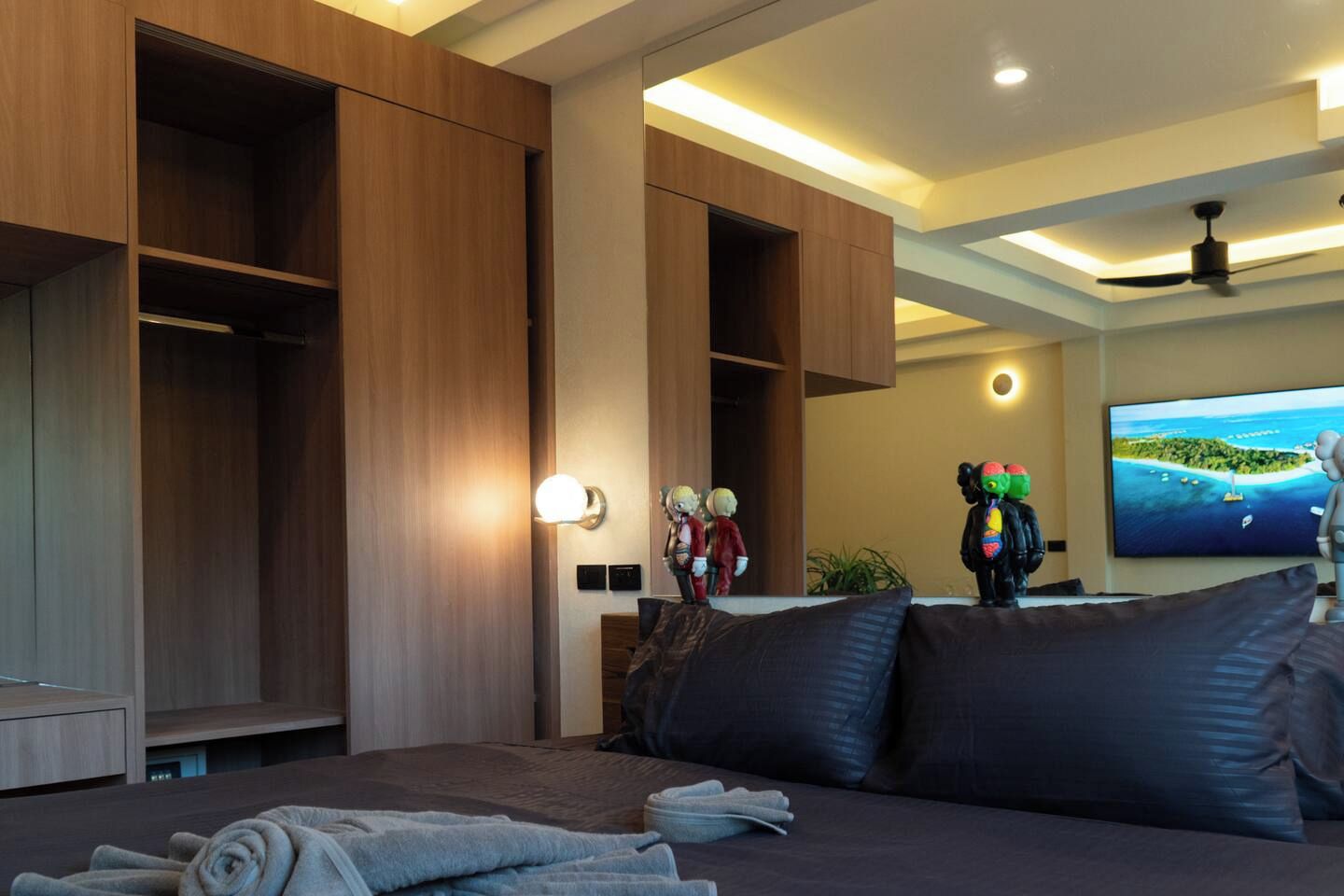 Une chambre d’hôtel équipée d’un lit, d’une télévision et de meubles de rangement en bois intégrés.
