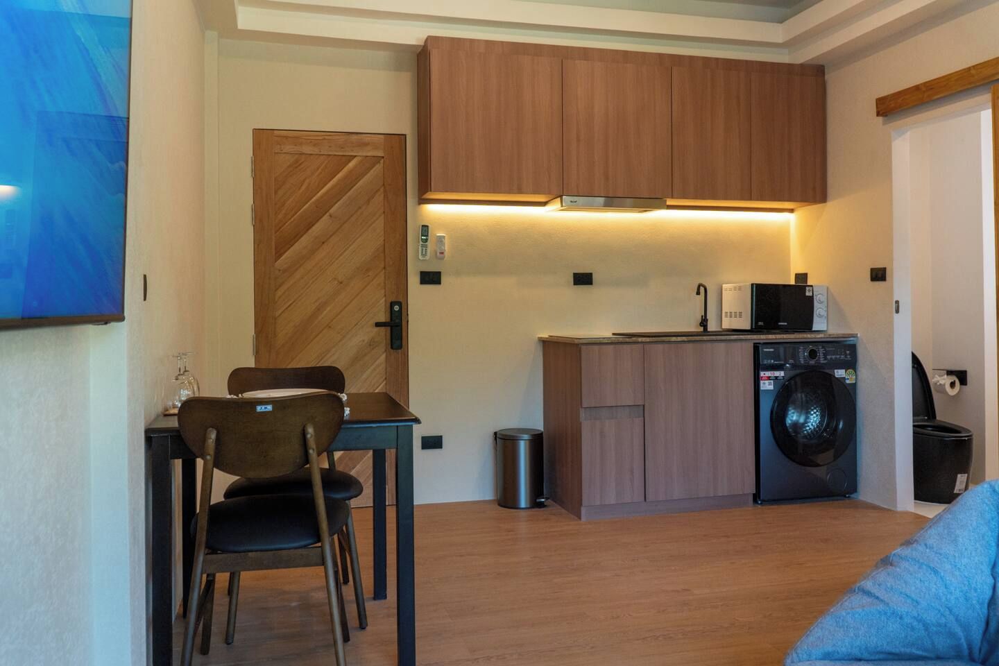 Une cuisine compacte avec des meubles en bois, un four à micro-ondes encastré et un lave-linge.