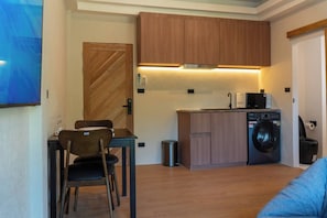 Une cuisine compacte avec des meubles en bois, un four à micro-ondes encastré et un lave-linge.