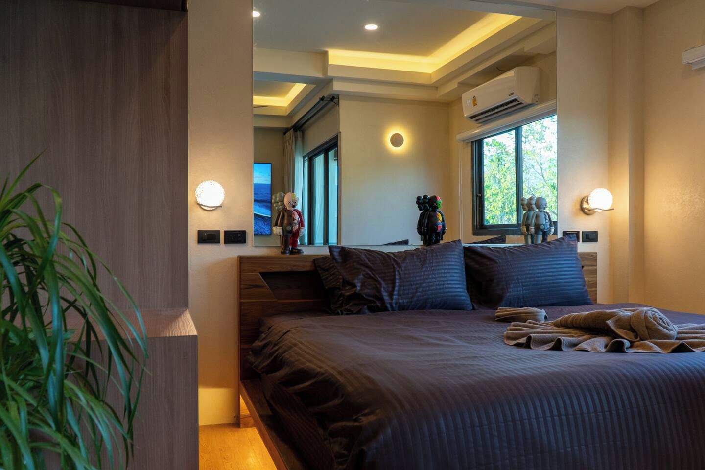 A modern bedroom with a large bed, bedside lamps, and a view of the outdoors.