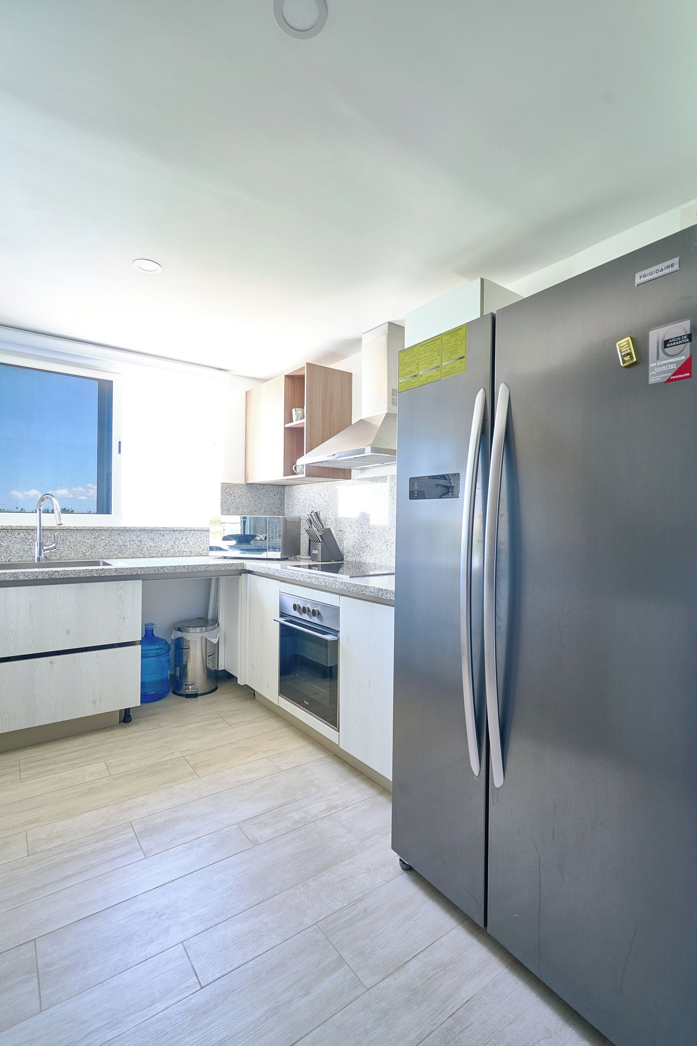 Eine moderne Küche mit Edelstahl-Kühlschrank, integriertem Backofen und einer Arbeitsplatte aus Granit.