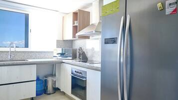 Eine moderne Küche mit Edelstahl-Kühlschrank, integriertem Backofen und einer Arbeitsplatte aus Granit.