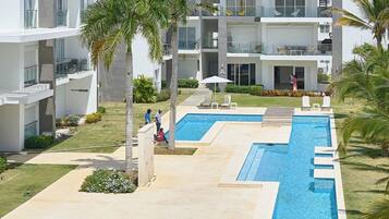 Ein modernes Resort mit mehreren Schwimmbecken, Palmen und blauem Himmel.