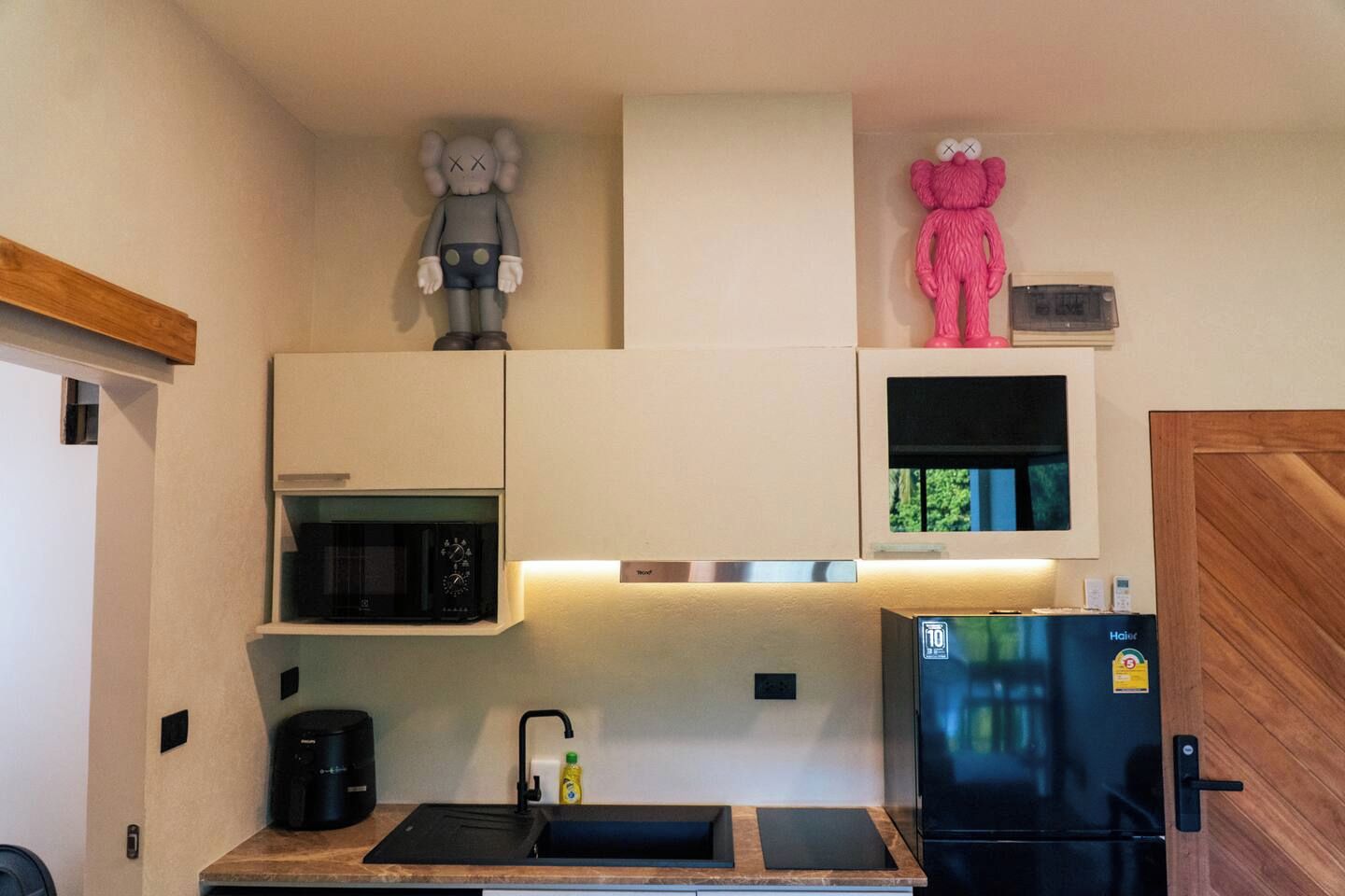 Een kleine keuken met een magnetron, een koelkast, een spoelbak en kastjes.