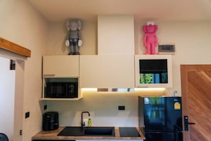 Eine kleine Küche mit Mikrowelle, Kühlschrank, Spüle und Schränken.