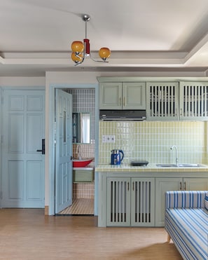 A kitchen with light blue cabinets, a red sink, and a blue kettle. - LangX Heaven Hotel & Apartment (Ngu Hanh Son)