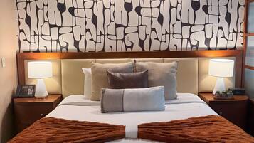 Una habitación de hotel con una cama grande, dos lámparas de noche, un teléfono y una pared con un diseño abstracto único.