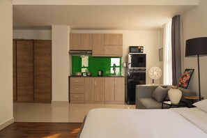 Ein modernes Hotelzimmer mit Küchenzeile, einer Couch, einem Bett und einem großen Fenster.