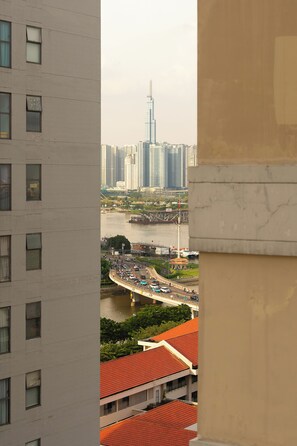 Ein Hochhaus mit zahlreichen Fenstern, Blick auf einen Fluss mit einer Brücke und einem entfernten Wolkenkratzer.
