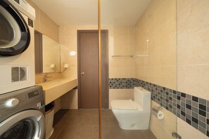 Ein kleines Badezimmer mit Waschmaschine, Toilette und Waschbecken.