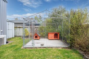 A fenced outdoor area with two wooden dog houses and a metal structure. - The Tin Hutt, Kinloch (Kinloch)