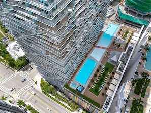 A high-rise building with multiple balconies, a swimming pool, and a landscaped area. - Luxury Apt in the Heart of Brickell – 44th Floor (Miami)