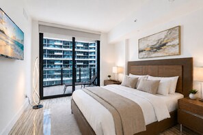 Una habitación de hotel moderna con una cama grande, vistas a un edificio alto y un cuadro en la pared.