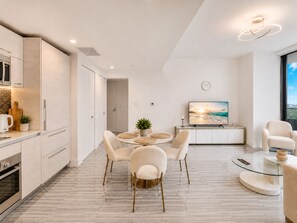 A modern kitchen with a dining area, a flat-screen TV, and a large window. - Luxury Apt in the Heart of Brickell – 44th Floor (Miami)