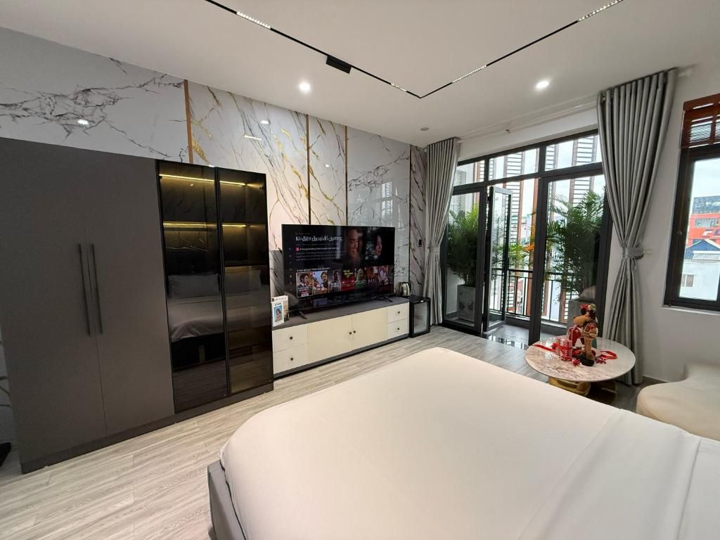A modern bedroom with a large bed, built-in wardrobe, a television, and a view of the outdoors.