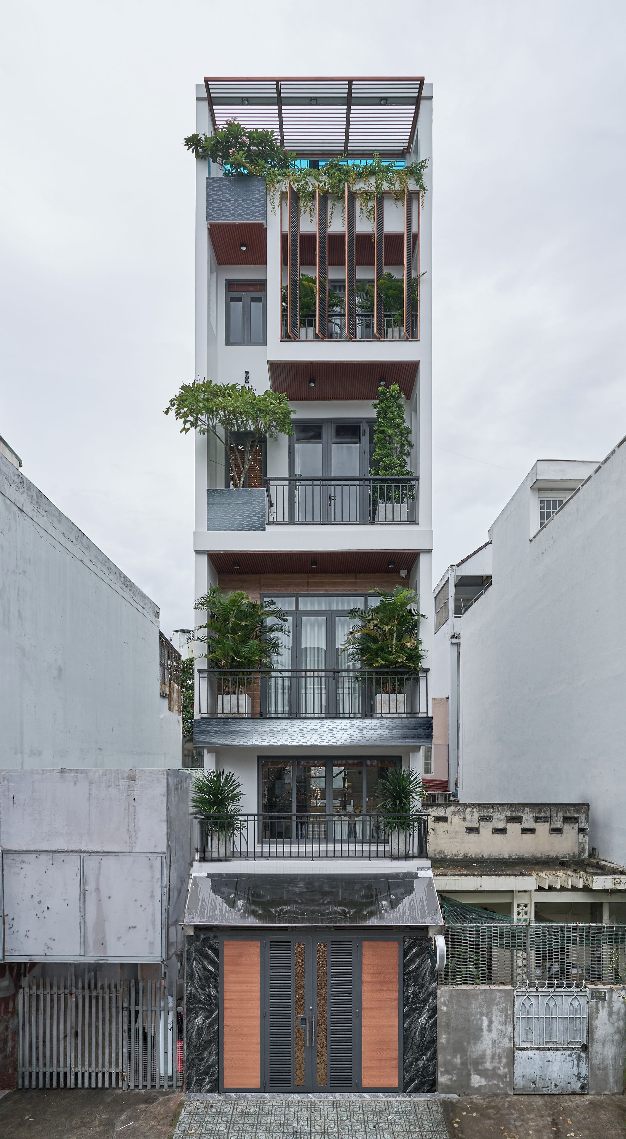 A multi-story residential building with balconies, a gated entrance, and a small front garden.