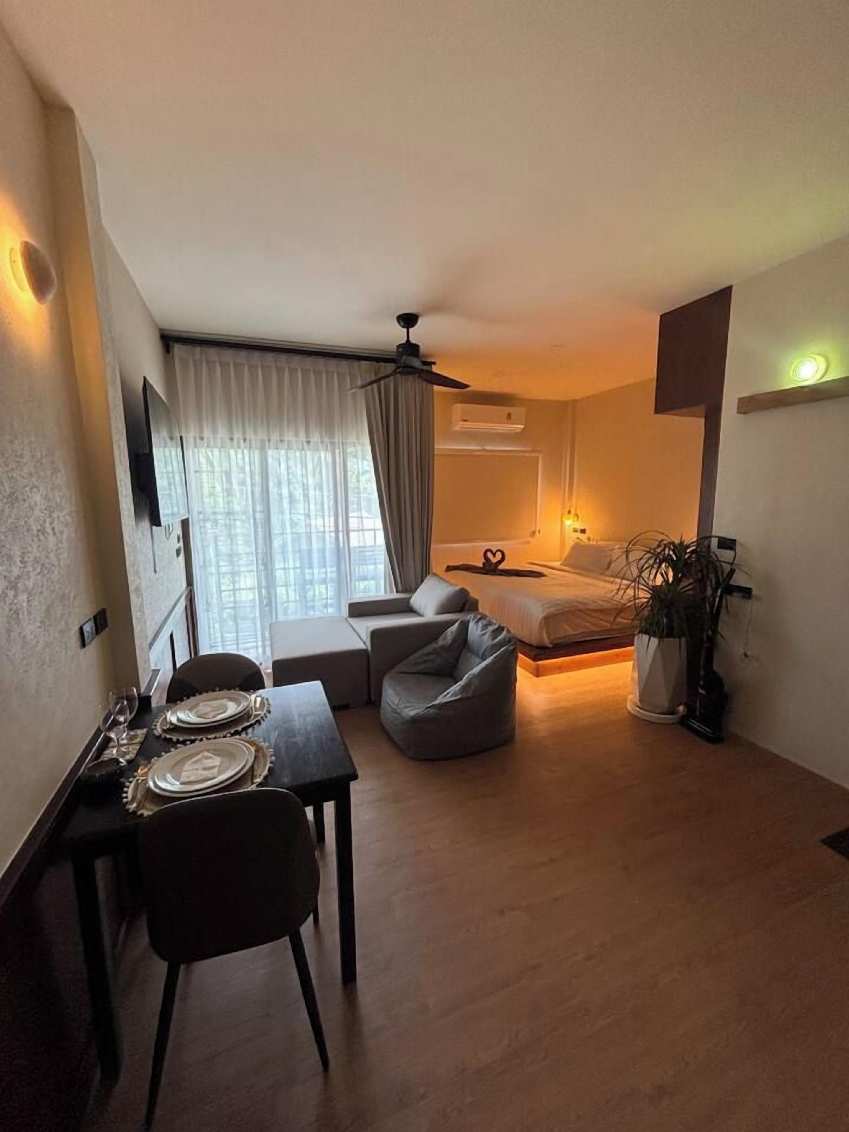 A compact living space with a dining area, a sofa, a bed, and a ceiling fan.