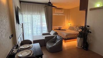A compact living space with a dining area, a sofa, a bed, and a ceiling fan.