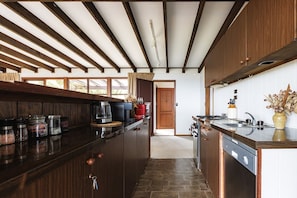 A kitchen with wooden cabinets, a built-in stove, and a large window. - Moonya Retreat | Valley Views, Fireplace & BBQ (Sydney)