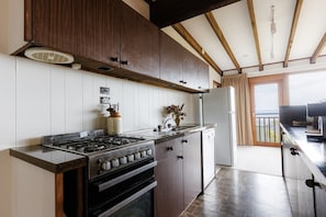 A kitchen with wooden cabinets, a gas stove, and a refrigerator.