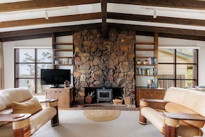 A cozy living room with a stone fireplace, leather sofas, and a flat-screen TV. - Moonya Retreat | Valley Views, Fireplace & BBQ (Sydney)