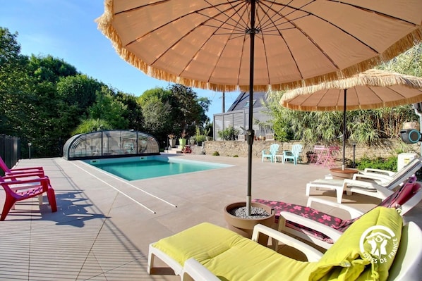 A pool area with lounge chairs, a covered seating area, and a glass-enclosed hot tub. - Canvases and Garden - PLUMELEC (PLUMELEC)