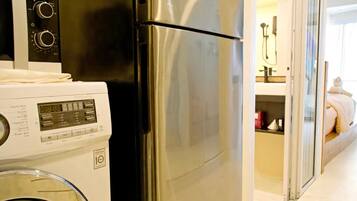 Une cuisine compacte équipée d’un réfrigérateur en acier inoxydable, d’un lave-linge et d’un four à micro-ondes.