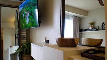 Een moderne keuken met een grote flatscreentelevisie, een houten kom op het aanrecht en een potplant.