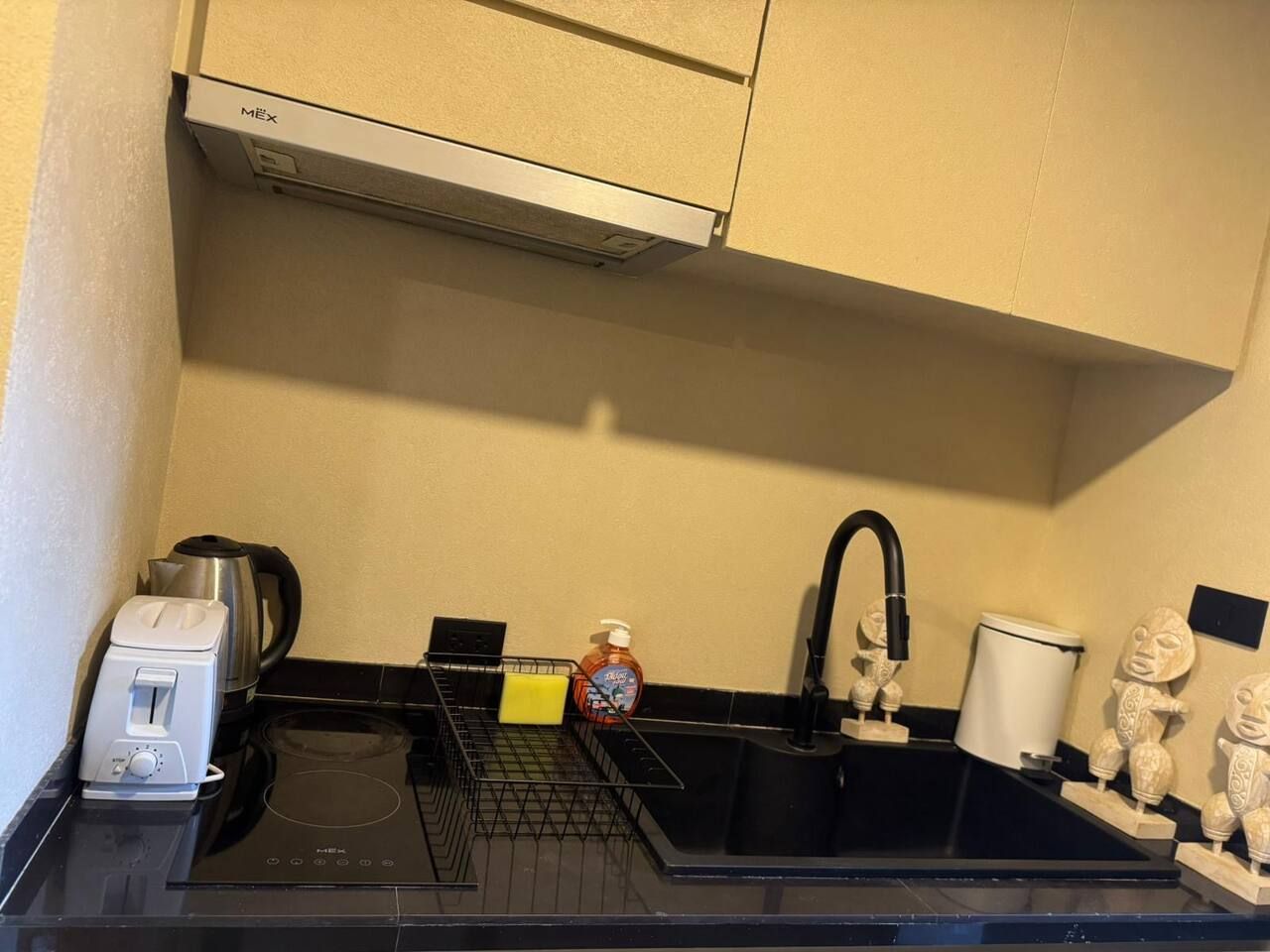 A compact kitchen with a toaster, kettle, sink, and decorative items.