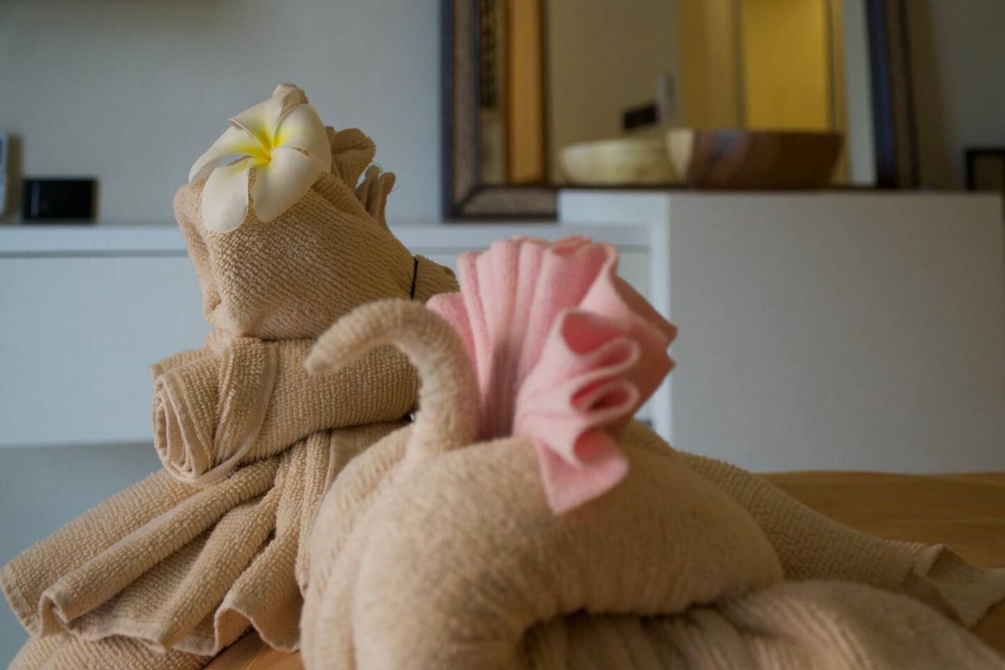 Une serviette ornée d’une fleur et un objet décoratif posés sur une surface en bois.