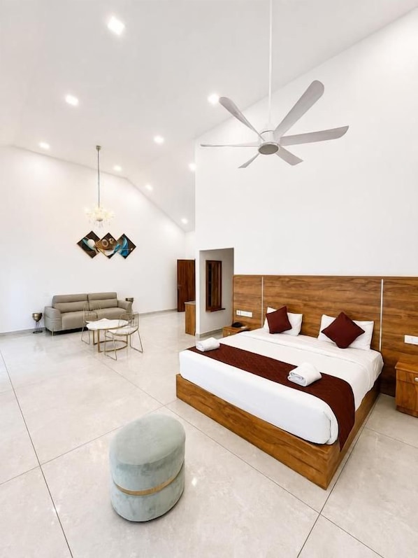 A modern bedroom with a large bed, a ceiling fan, and a chandelier. - Skybz Munnar (Devikolam)