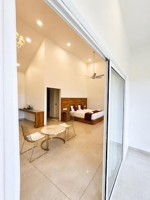 A modern bedroom with a bed, bedside table, and a desk area with a chair. - Skybz Munnar (Devikolam)