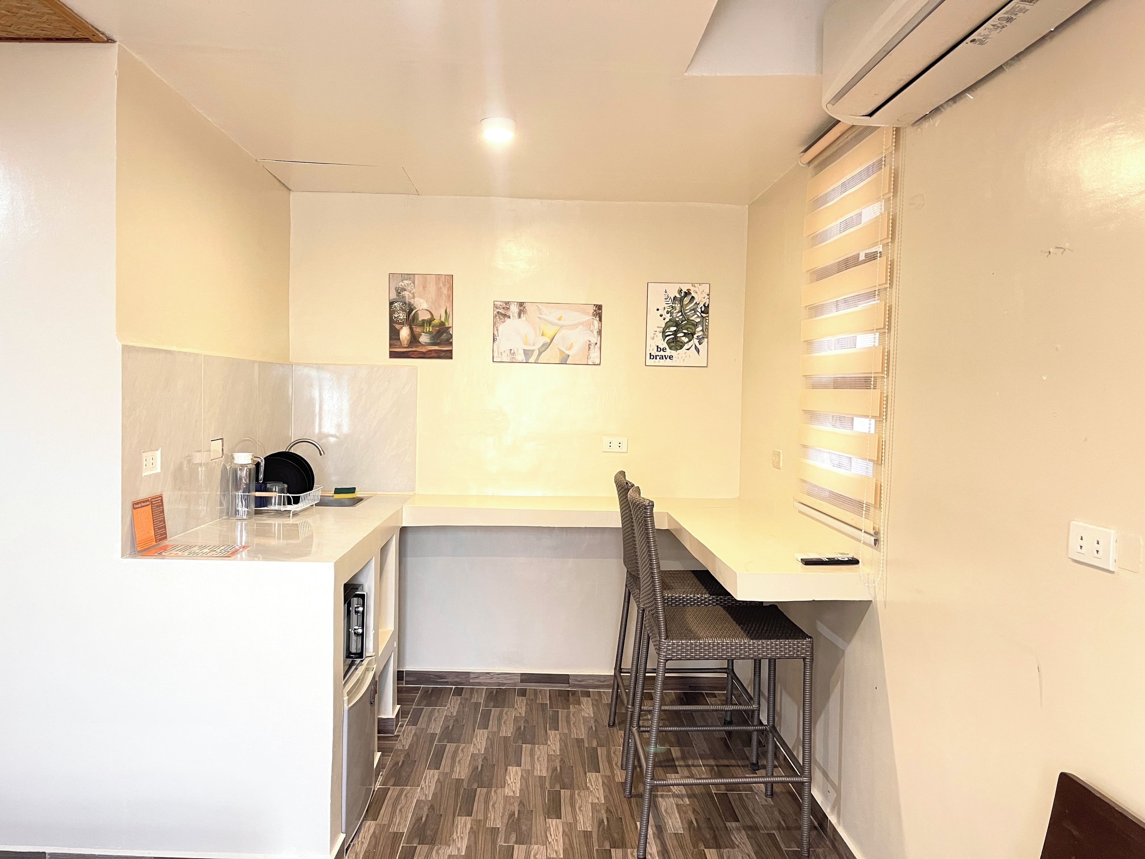 Une cuisine compacte comprenant un évier, un petit coin repas avec une chaise et un climatiseur fixé au mur.