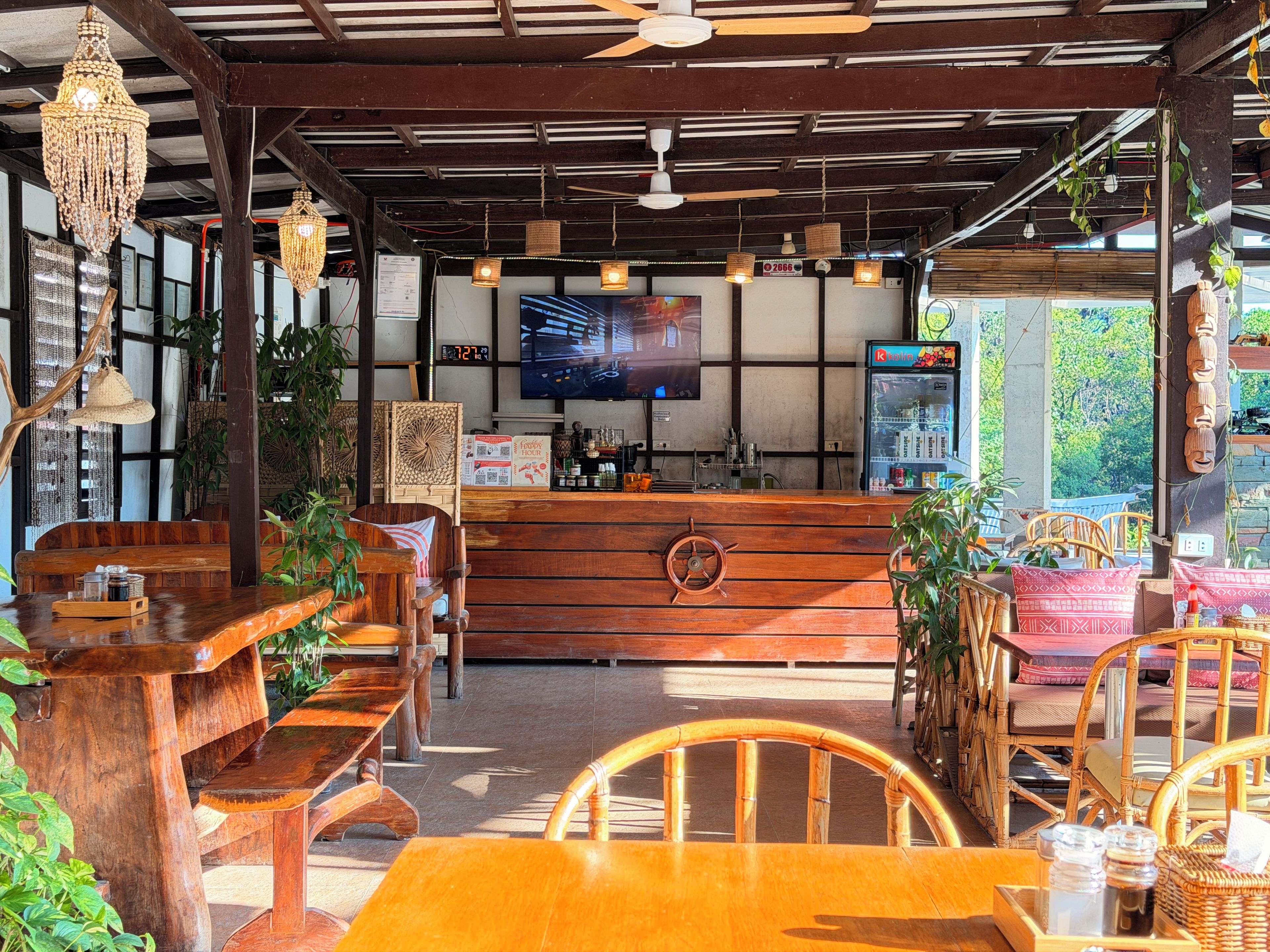 A restaurant with wooden furniture, a bar area, and a television screen.