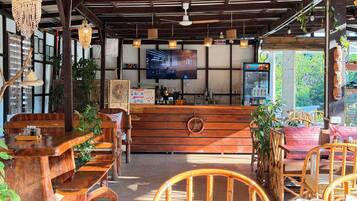 A restaurant with wooden furniture, a bar area, and a television screen.