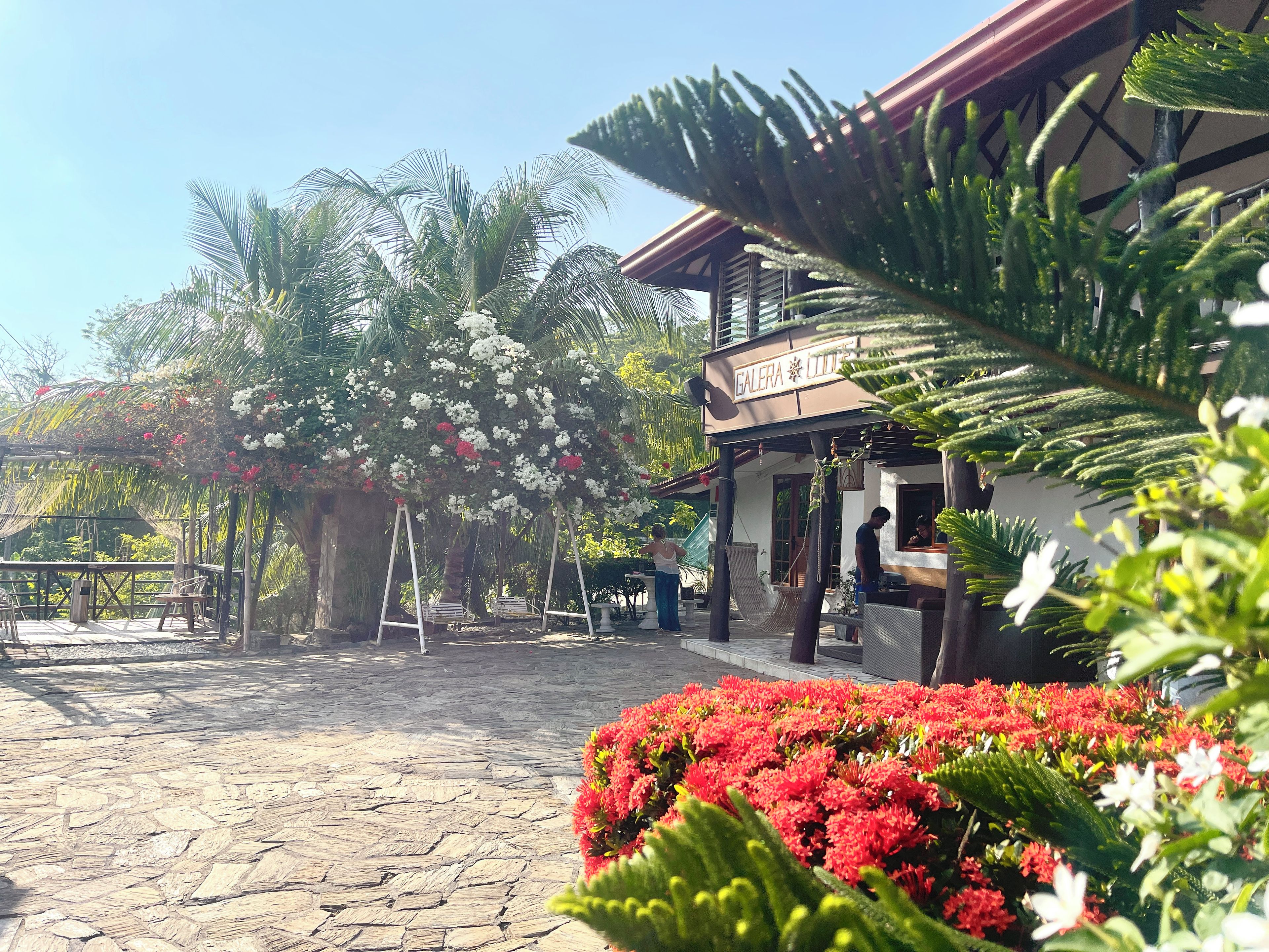 A courtyard with a stone floor, a hanging chair, and a building with a sign that reads 'GALERA SULTA'.