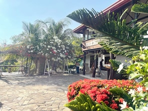 A courtyard with a stone floor, a hanging chair, and a building with a sign that reads 'GALERA SULTA'. - Galera Lodge & Cafe (Puerto Galera)