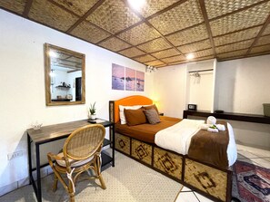 A hotel room with a bed, a desk, a chair, a mirror, and a ceiling with a woven pattern.