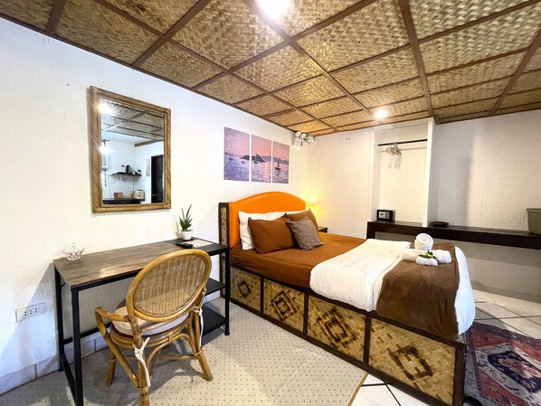 A hotel room with a bed, a desk, a chair, a mirror, and a ceiling with a woven pattern.